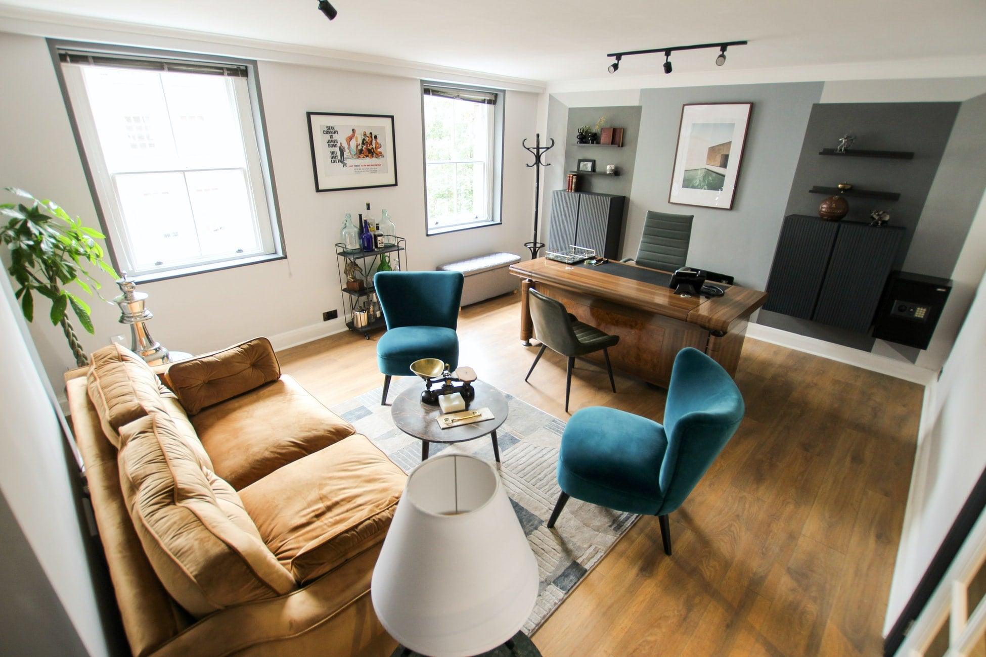 A warm living room with a plush brown couch and two blue upholstered chairs