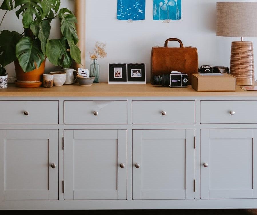 A grey wall cabinet with a wooden top and multiple drawers and storage sections