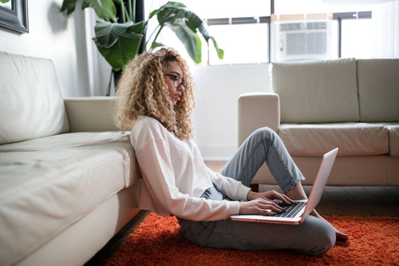 a young woman sitting on a rug, working from home