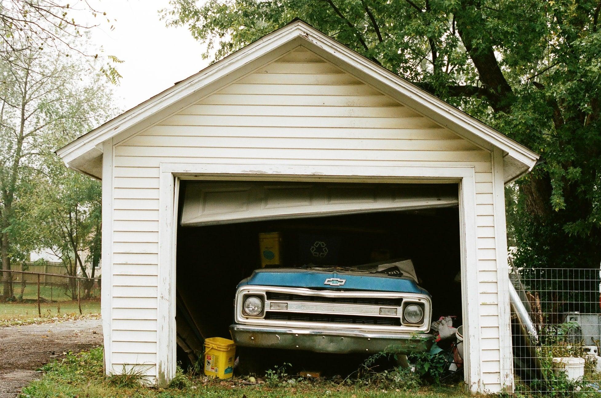 An unused garage with a car popping out and a broken door