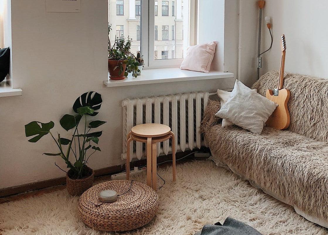 A warm sitting area overlooking a window with a shaggy couch and a guitar