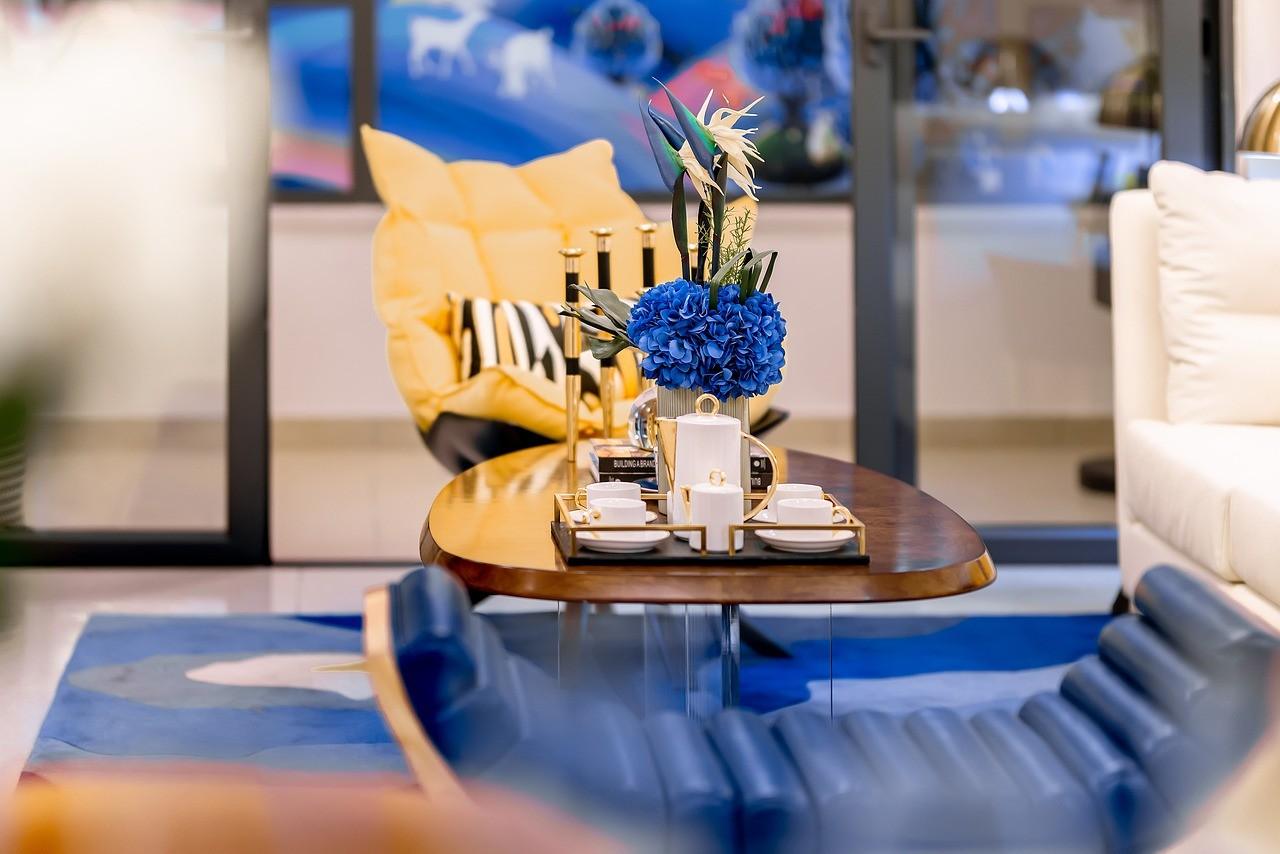 A wooden center table with a flower vase and a tray with teacups on it